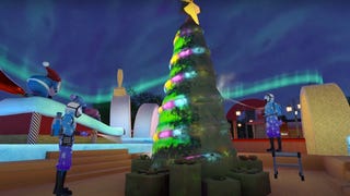 Two PowerWash players are spraying a filthy Christmas tree, revealing a bright, colourful tree beneath