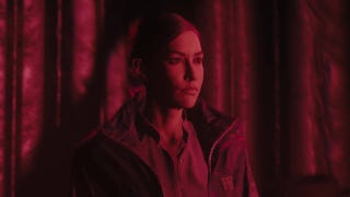 Kiran Estevez stands bathed in a red light in Alan Wake 2's The Lake House DLC.